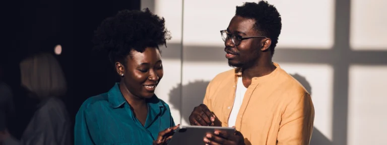 Two people smiling down looking at tablet.webp