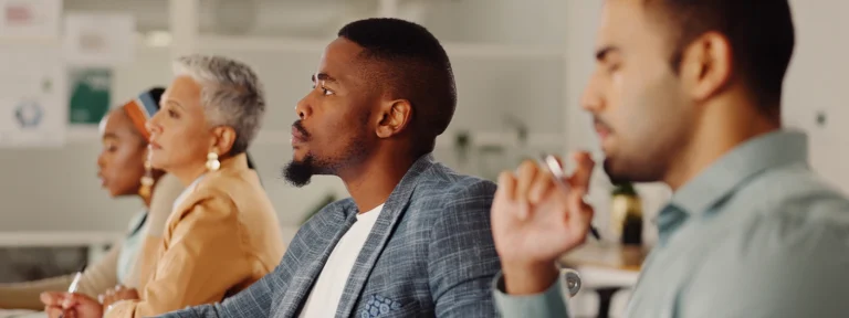 Develop a business case for AI (which your CFO will approve) People sitting at table looking ahead one person in focus.webp